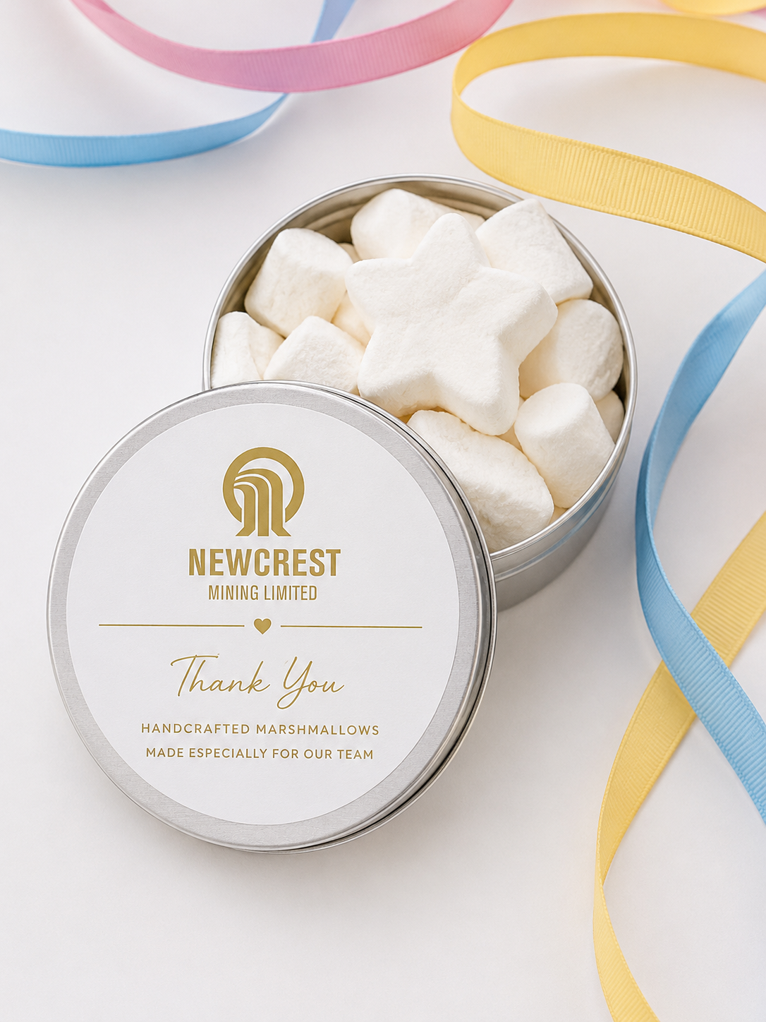 A branded corporate gift tin filled with star shaped handcrafted marshmallows and pastel ribbons
