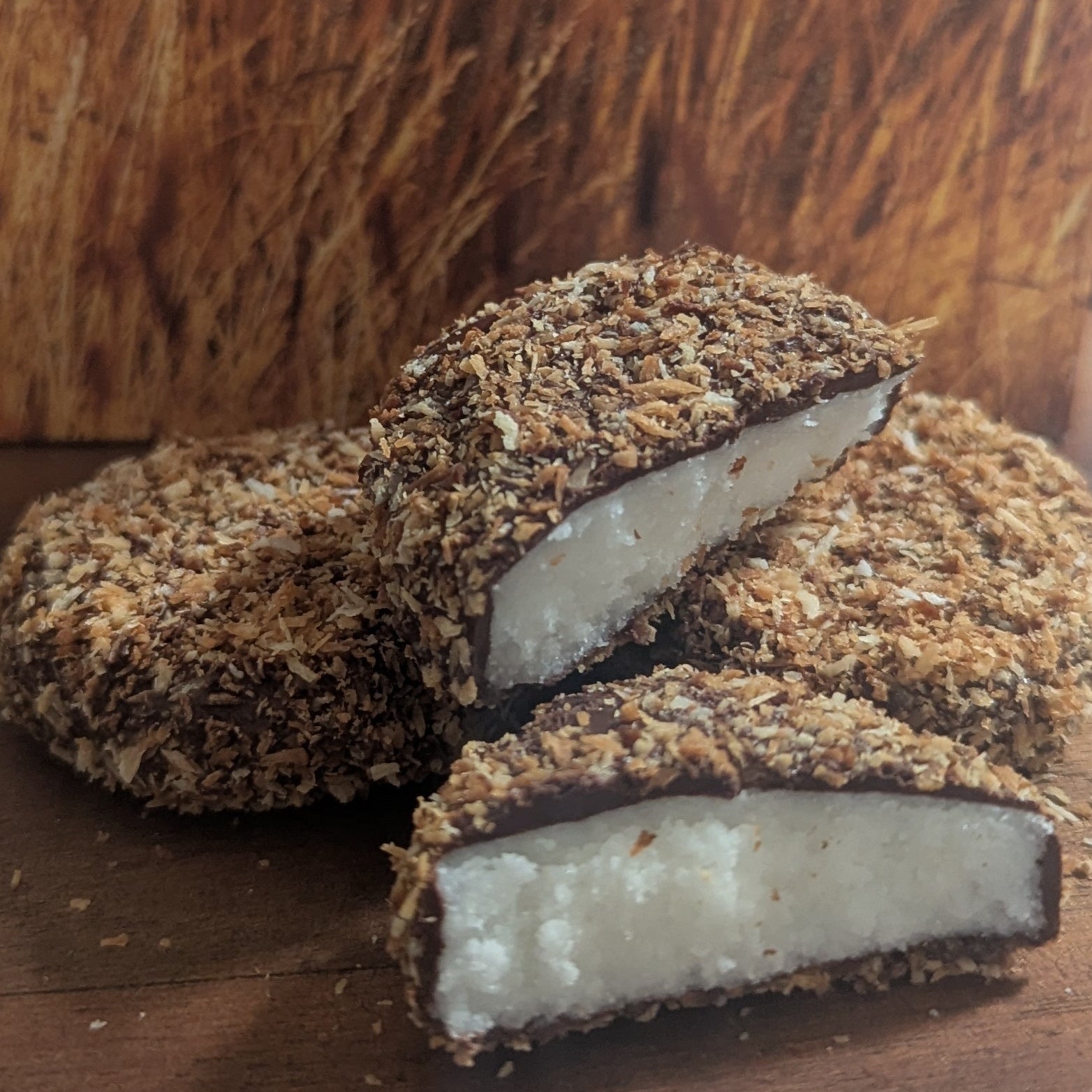 Coconut crumbed macaroon bars cut open to show the soft white centre on a timber board