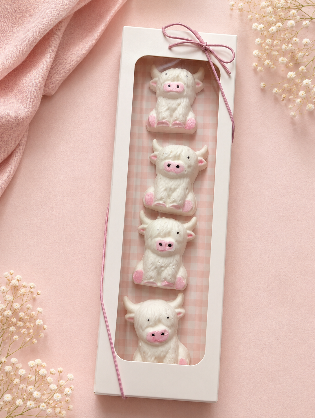 Four handcrafted Highland cow marshmallows in a white window gift box tied with pink ribbon